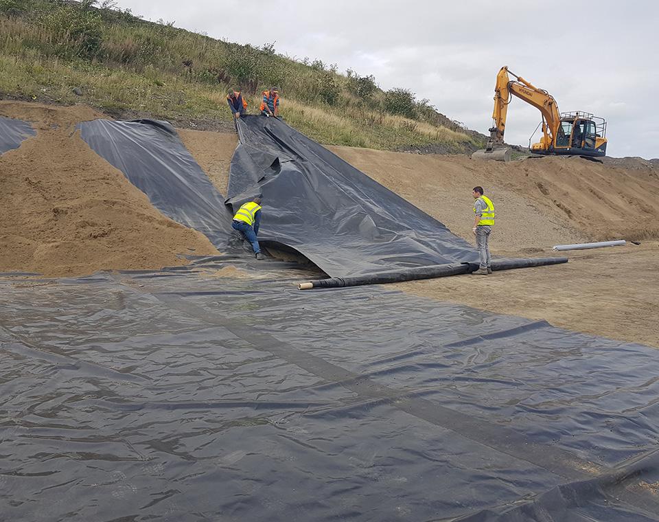 men covering ground with large plastic covers